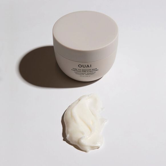 OUAI hair product jar with a sample of cream on a light background
