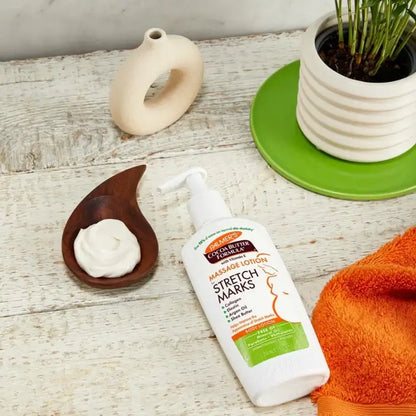 Palmer's Cocoa Butter Formula stretch mark lotion on a wooden surface with a plant and towel.