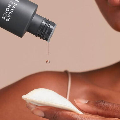 Paula’s Choice Skin Perfecting 2% BHA Liquid Exfoliant drips onto a cotton pad for skincare application.