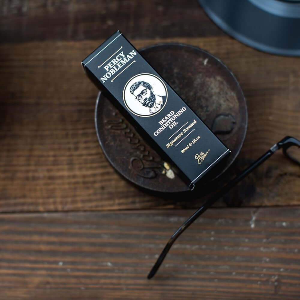 Percy Nobleman Barber shop product packaging on a wooden surface with a vintage camera.