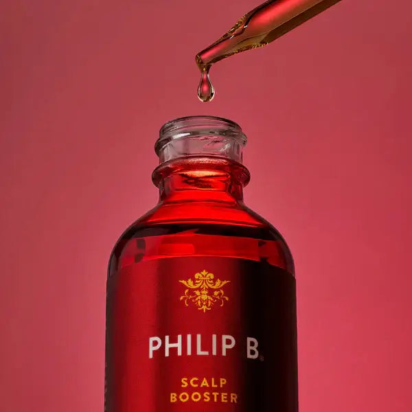 PHILIP B Scalp Booster 60ml bottle with dropper against a red background, showcasing hair treatment for scalp health.