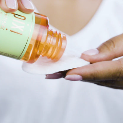 Person pouring PIXI from a bottle onto a white surface