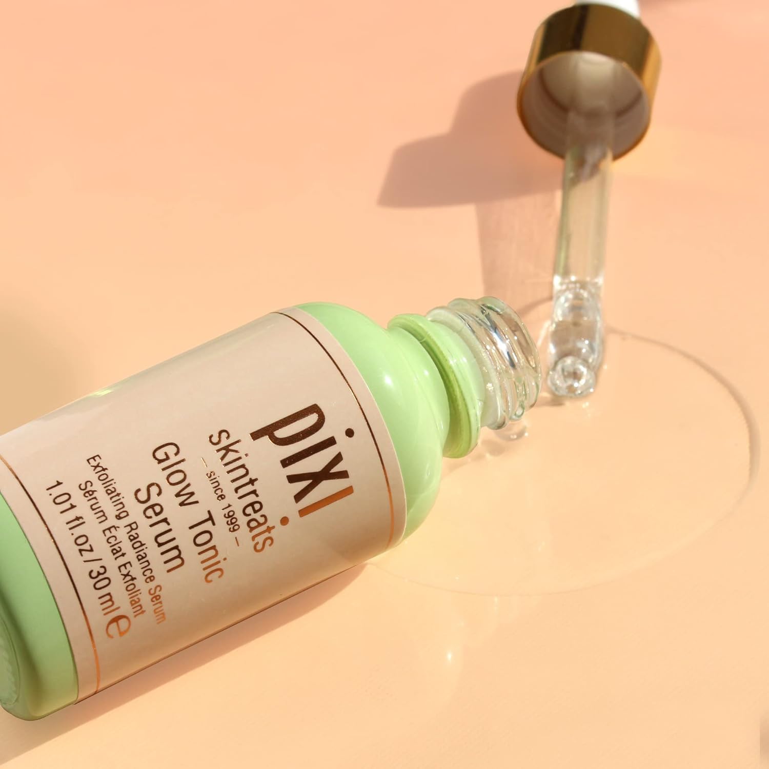 Pixi Glow Tonic Serum bottle with dropper on a peach background