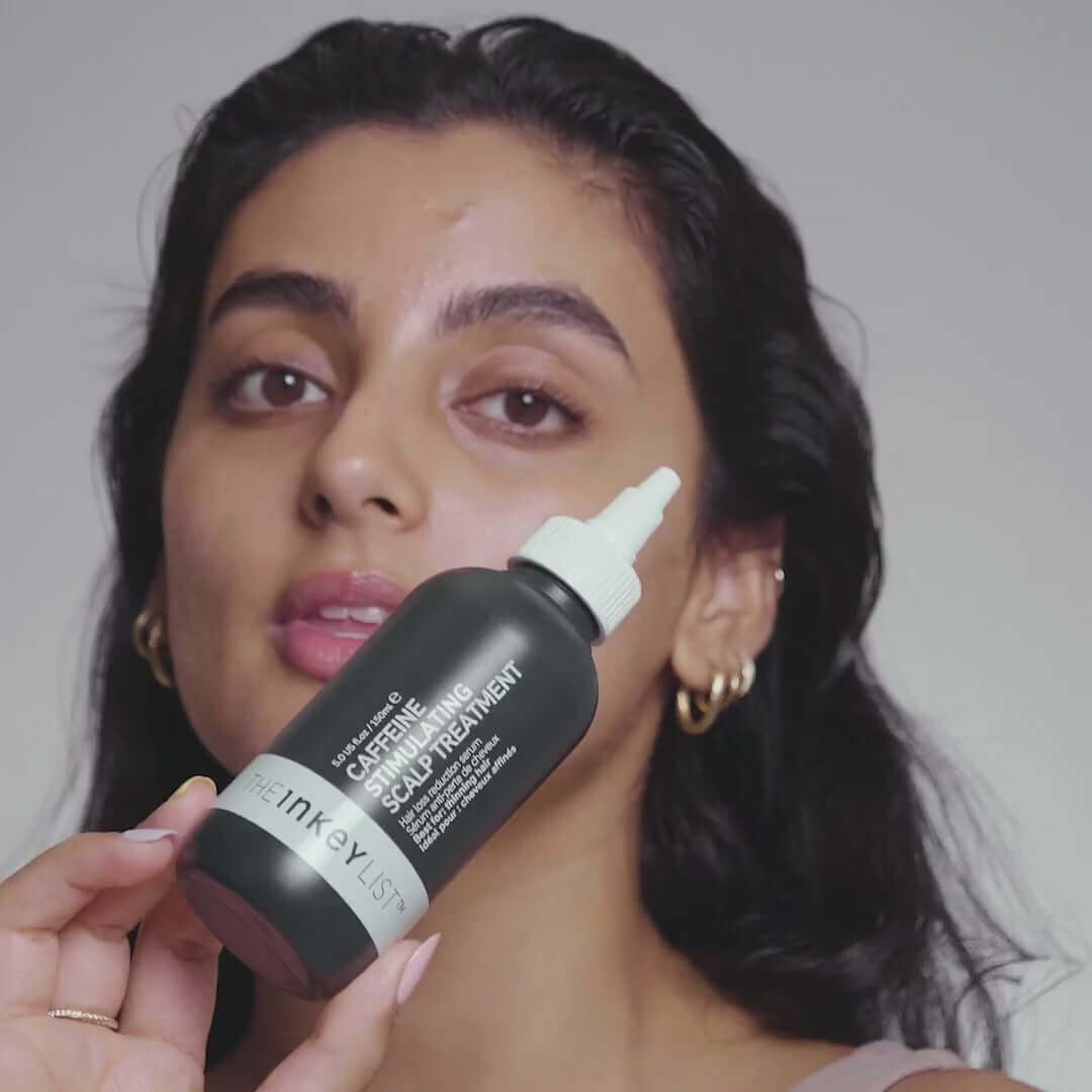 Person applying The INKEY List Caffeine Stimulating Scalp Treatment for healthier hair.