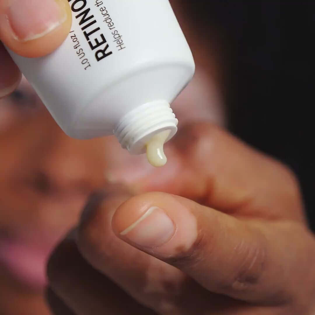Close-up of a hand holding The INKEY List Retinol bottle, showcasing a small droplet of retinol cream.