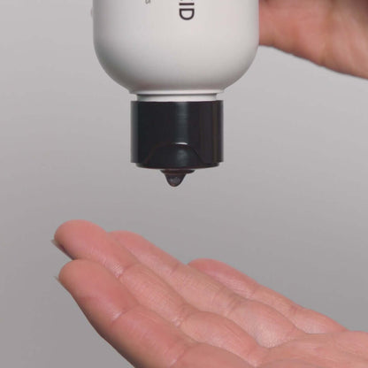 Drop of skincare product from a bottle into an open hand, showcasing a skincare routine for oily skin.