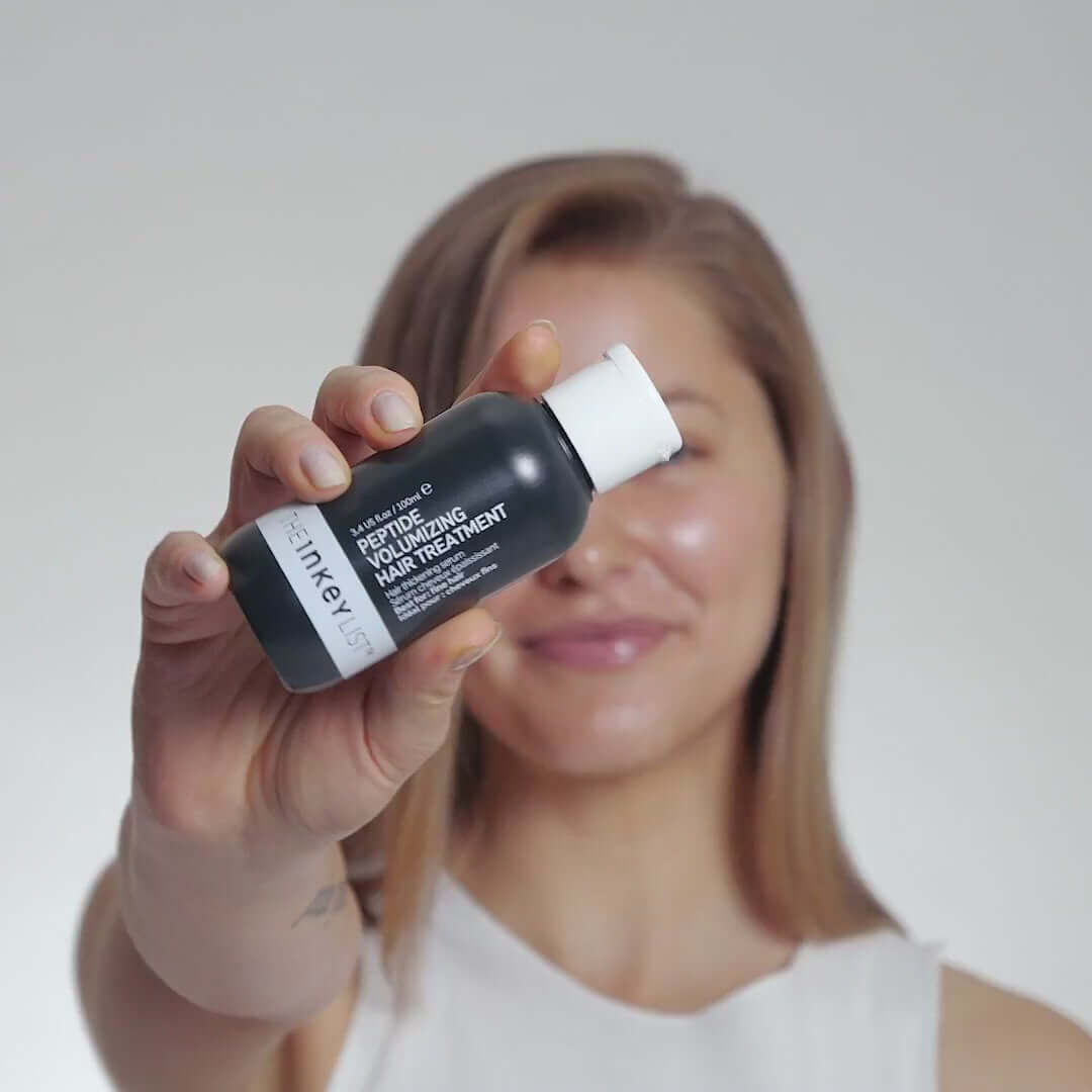 The INKEY List Peptide Volumizing Hair Treatment 100ml held by a woman, showcasing its volumizing benefits for hair.