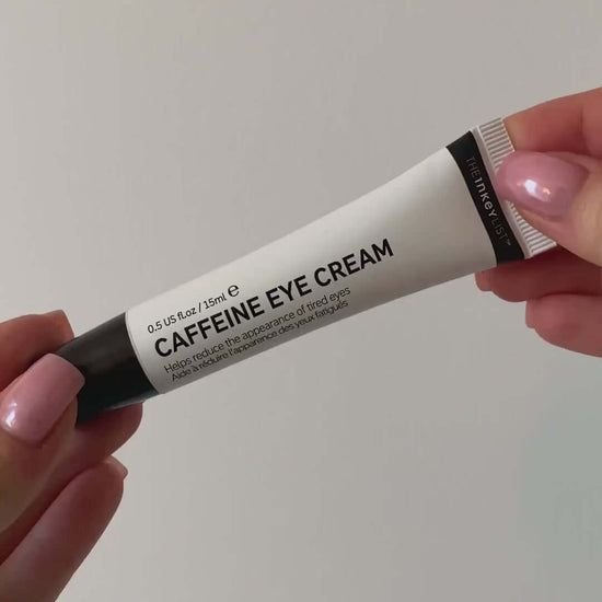 The INKEY List Caffeine Eye Cream 15ml tube held in hand, designed to reduce tired eyes and brighten the under-eye area.