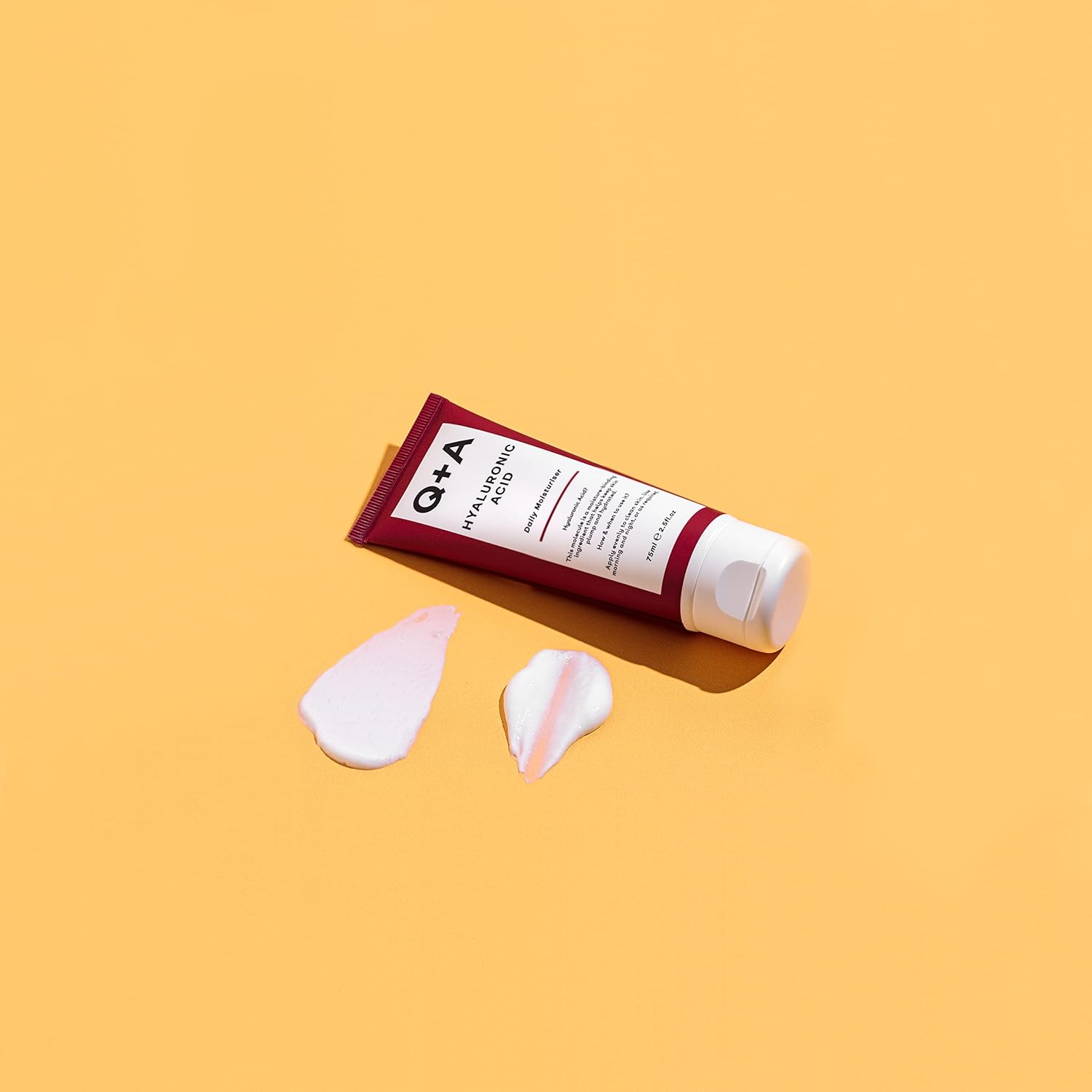 Tube of Q+A hair product with application samples on a yellow background