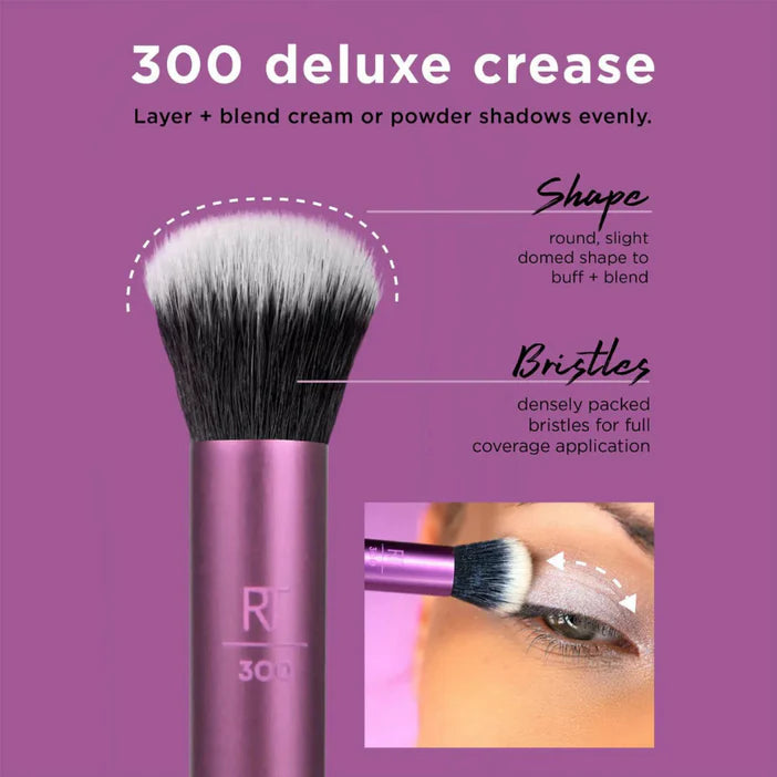 Real Techniques Makeup brush with purple handle and white bristles on a purple background, featuring text about brush use.