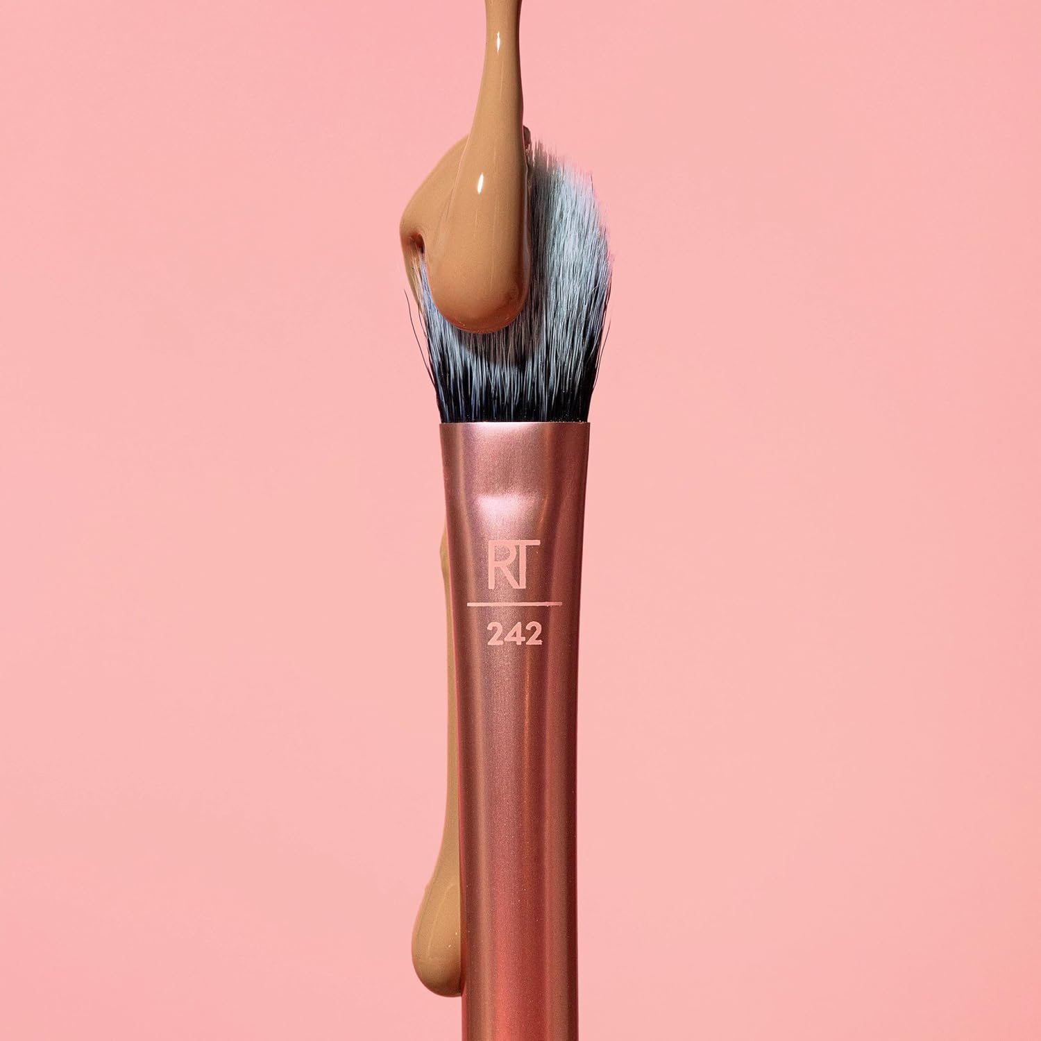 Makeup brush with a wooden handle and pink ferrule on a pink background