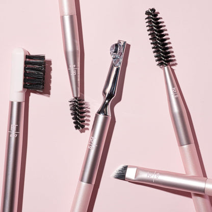 Real Techniques Set of makeup brushes with pink and silver handles on a pink background