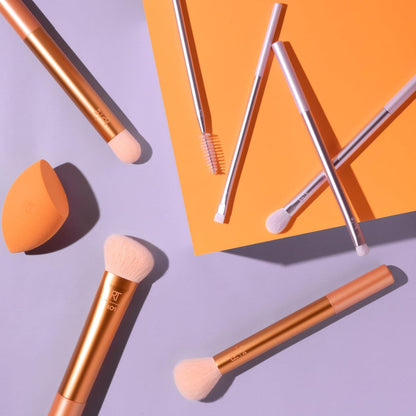 Makeup brushes and a sponge on a purple and orange background