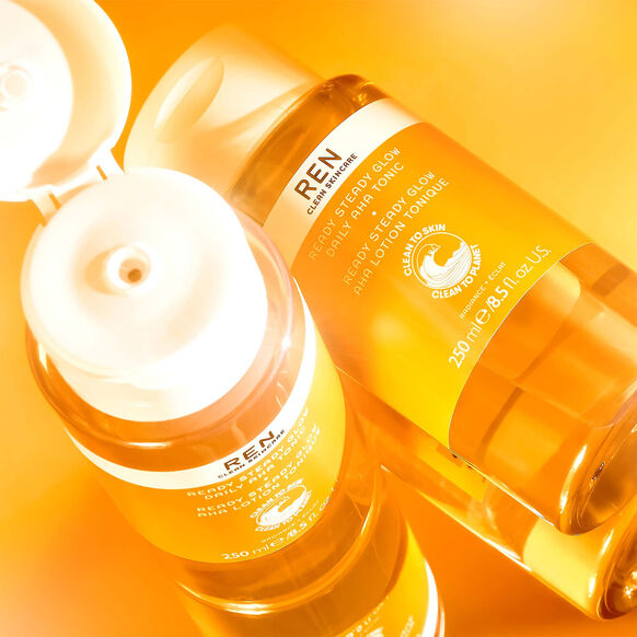 Two bottles of REN skincare products on a bright orange background