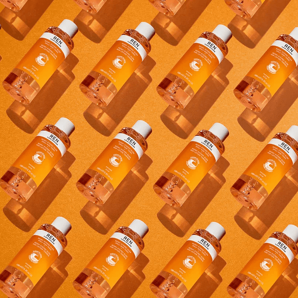 REN Clean Skincare Ready Steady Glow Daily AHA Tonic bottles arranged on an orange background for a bright, fresh look.