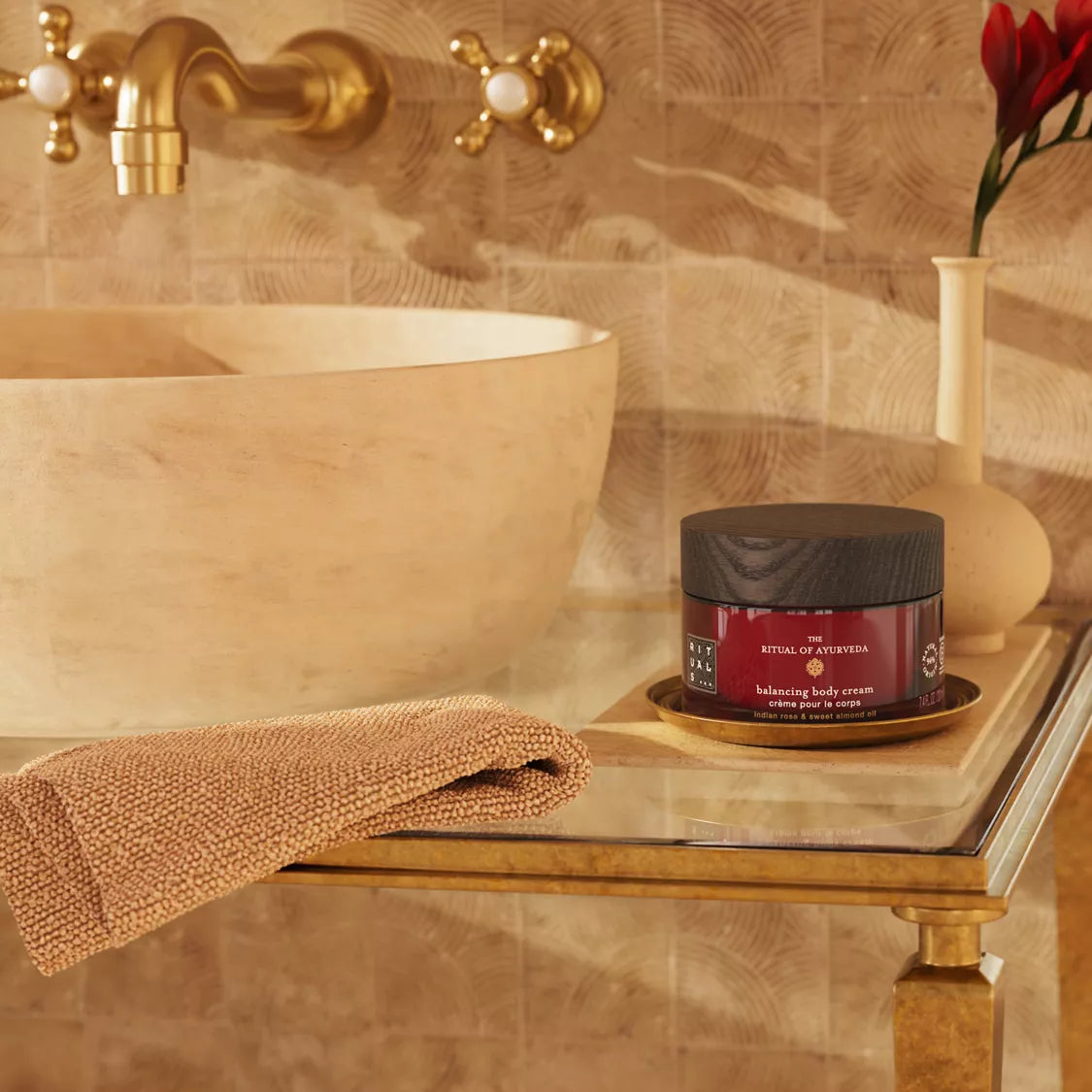 Bathroom setting with a jar of body cream, towel, and vase on a shelf.