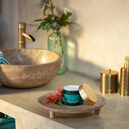 RITUALS - The Ritual of Karma Body Cream displayed on a wooden platter in a serene bathroom setting.