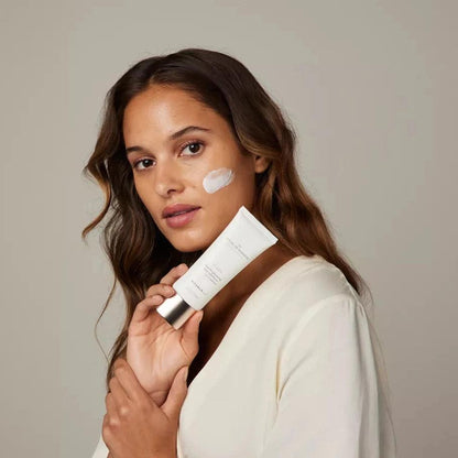 Model applying RITUALS The Ritual of Namaste Skin Brightening Face Exfoliator for a radiant complexion.