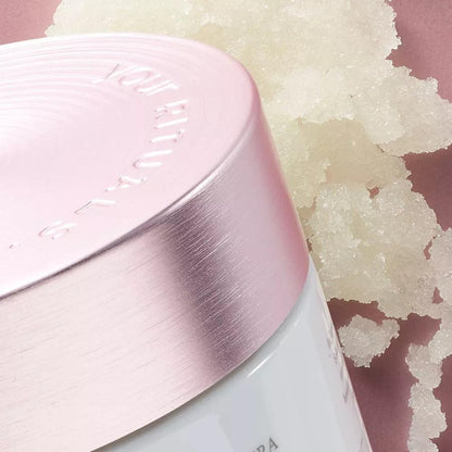 RITUALS The Ritual of Sakura Sugar Body Polish jar with sugar scrub in background on soft pink surface.