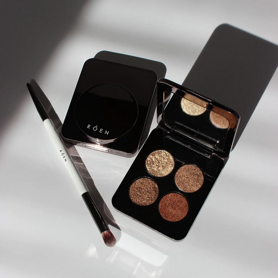 RÓEN  Makeup palette with four shades and a brush on a reflective surface, featuring the brand 'Röen'.