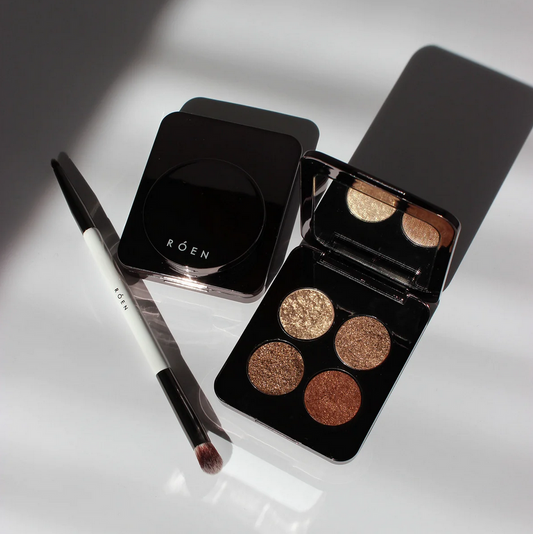 RÓEN  Makeup palette with four shades and a brush on a reflective surface, featuring the brand 'Röen'.
