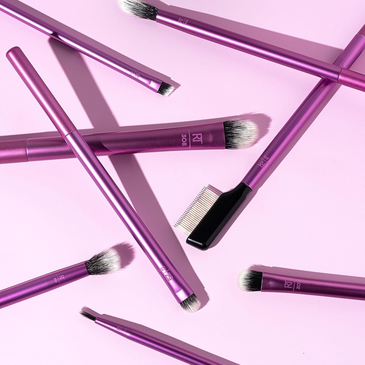 Purple makeup brushes with 'RT' branding on a pink background