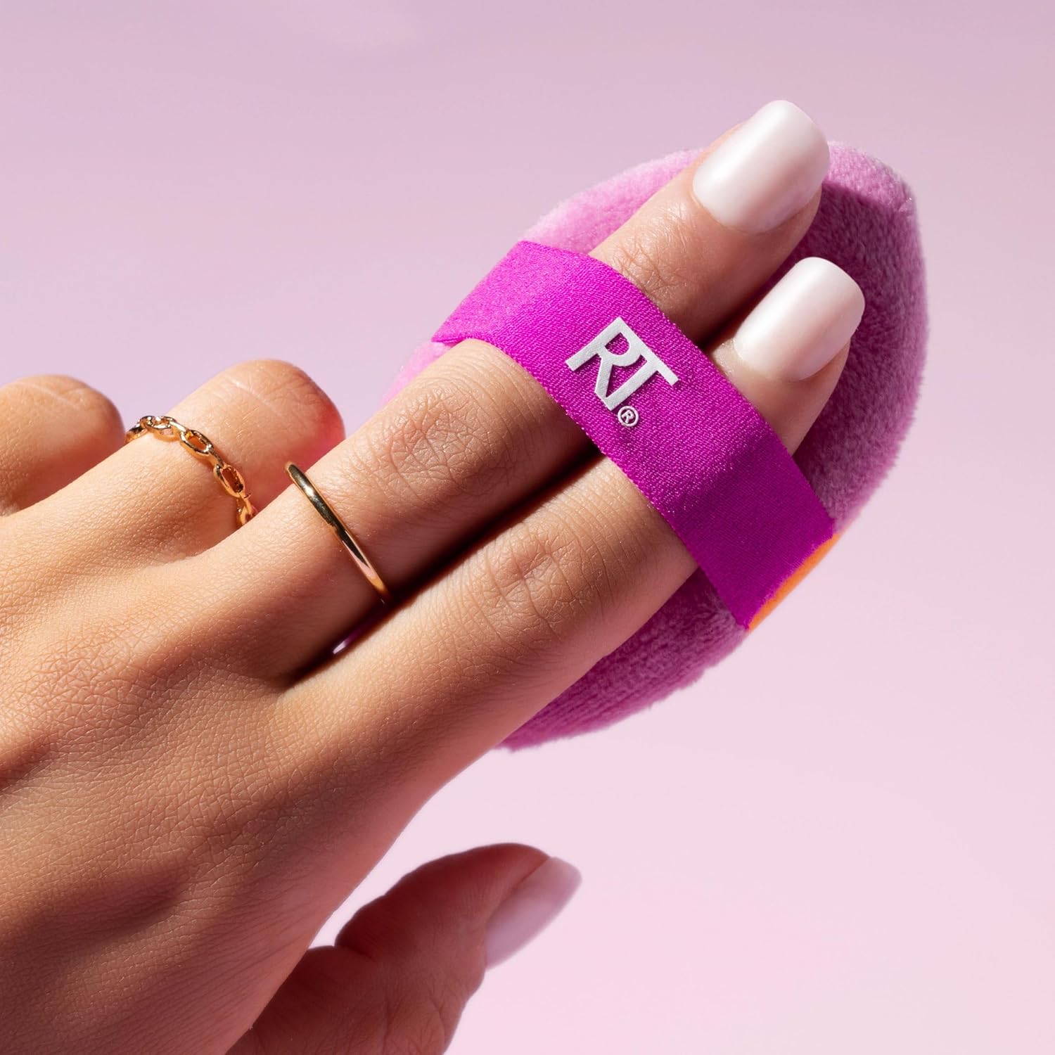 Hand wearing a purple finger sleeve with a logo on a pink background