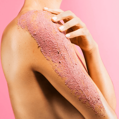 Application of Sand & Sky Australian Pink Clay Smoothing Body Sand on a shoulder against a pink background.