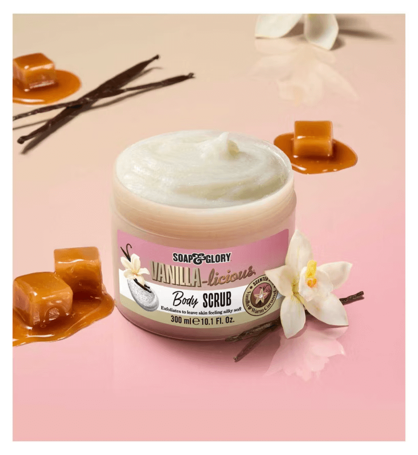 Soap & Glory Vanilla-licious Body Scrub in a jar surrounded by vanilla pods and caramel, offering a luxurious bath experience.