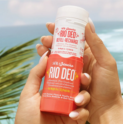 Sol de Janeiro Rio Deo Aluminum-Free Deodorant Cheirosa 40 held by a person against a scenic beach background.