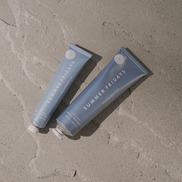 Two blue tubes of 'Summer Fridays' product on a textured beige surface