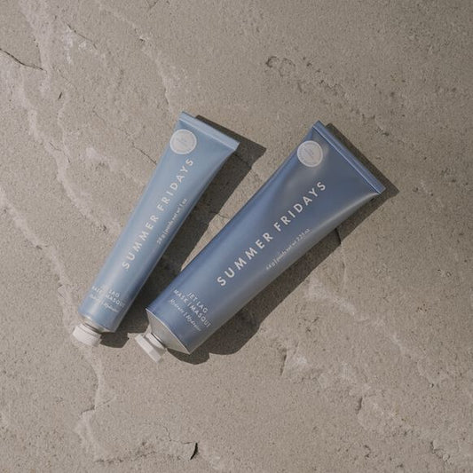 Two blue tubes of 'Summer Fridays' product on a textured beige surface