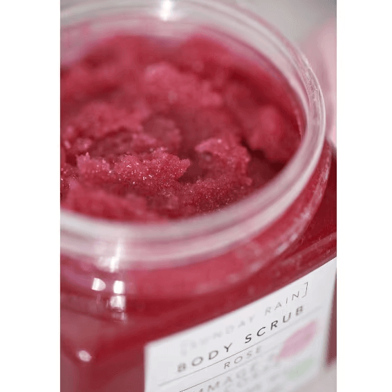 Close-up of SUNDAY RAIN Rose Body Scrub showcasing vibrant red scrub texture in a jar.