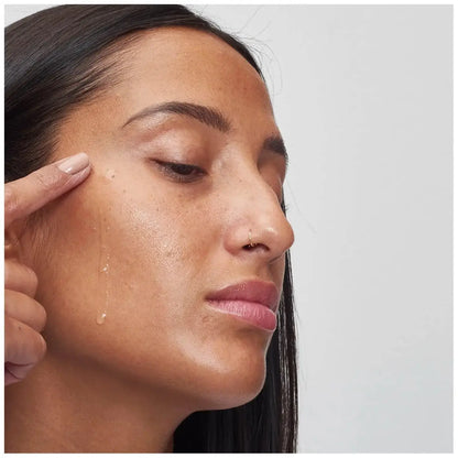 Woman applying The INKEY List Beta Hydroxy Acid Serum on her cheek for radiant skin.
