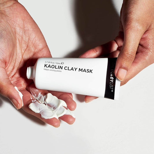 Hands holding a tube of The Inkey List Kaolin Clay Mask with visible product on fingers against a white background