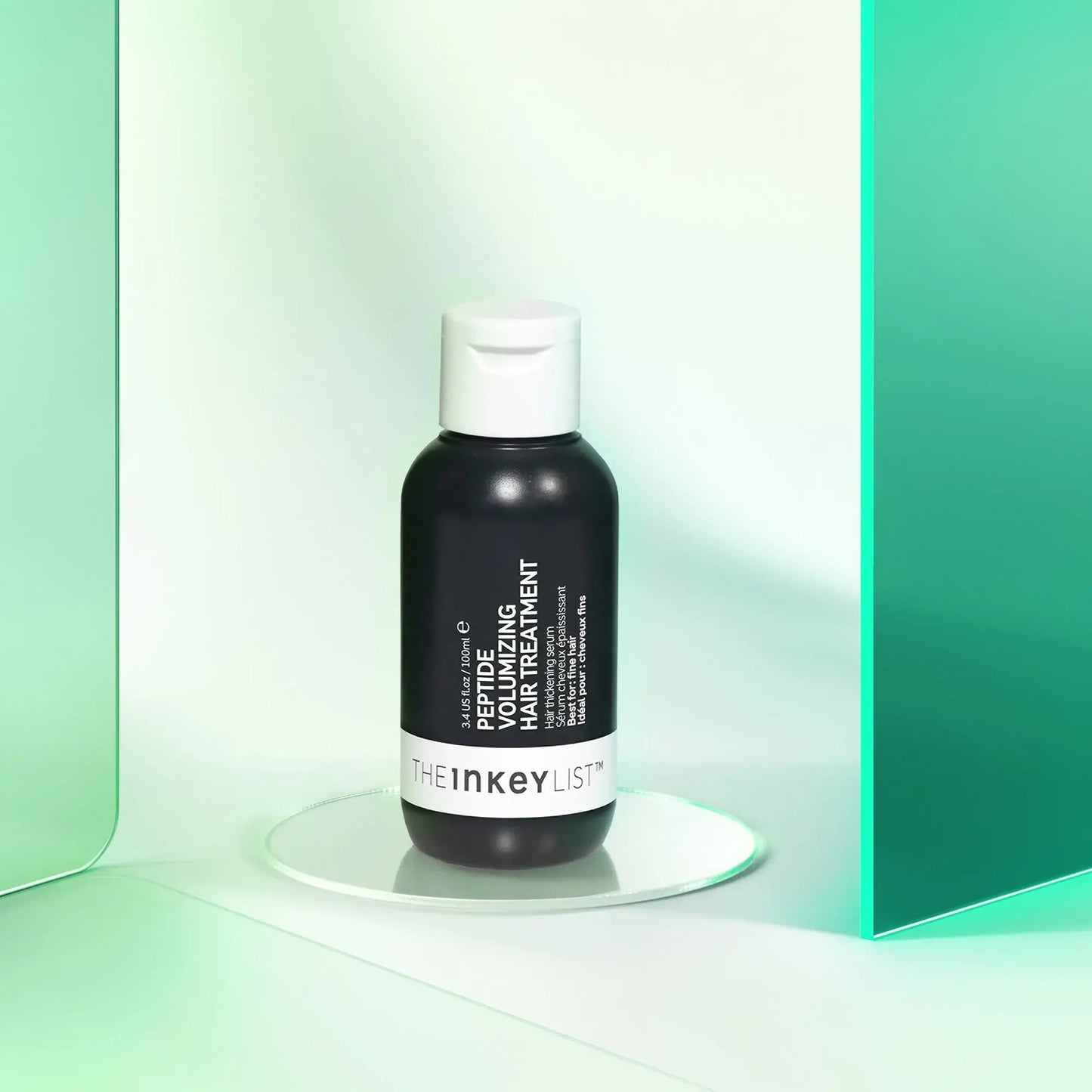 The INKEY List Peptide Volumizing Hair Treatment 100ml in a sleek bottle on a mirrored surface.