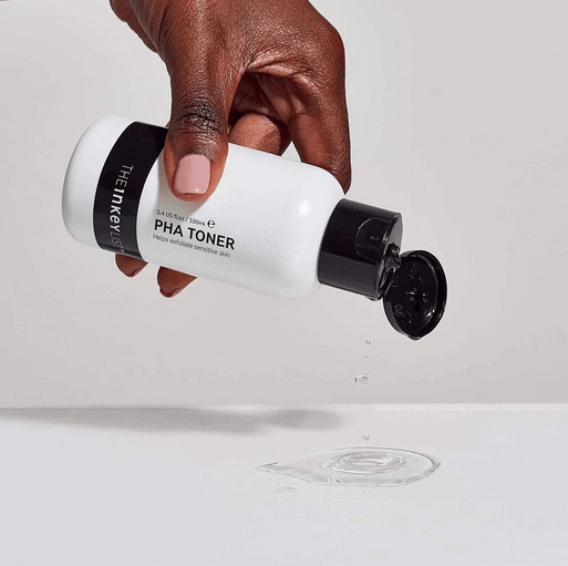 Hand pouring The INKEY List PHA Toner 100ml, promoting healthy and radiant skin for sensitive skin types.