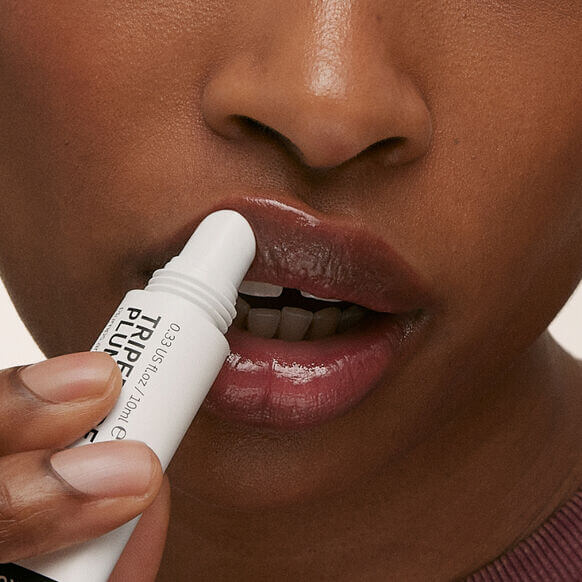Close-up of a person applying The INKEY List Tripeptide Plumping Lip Balm for hydrated, luscious lips.