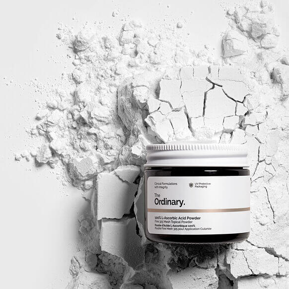 The Ordinary 100% L-Ascorbic Acid Powder jar against a textured white background of powder, showcasing its revitalizing skincare benefits.