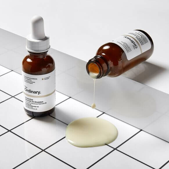 The Ordinary Granactive Retinoid 2% Emulsion bottle with serum dripping on a tiled surface, for youthful skin.