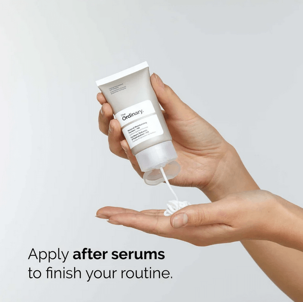 Person applying The Ordinary Natural Moisturising Factors + HA moisturizer to hand after serums for skincare routine.