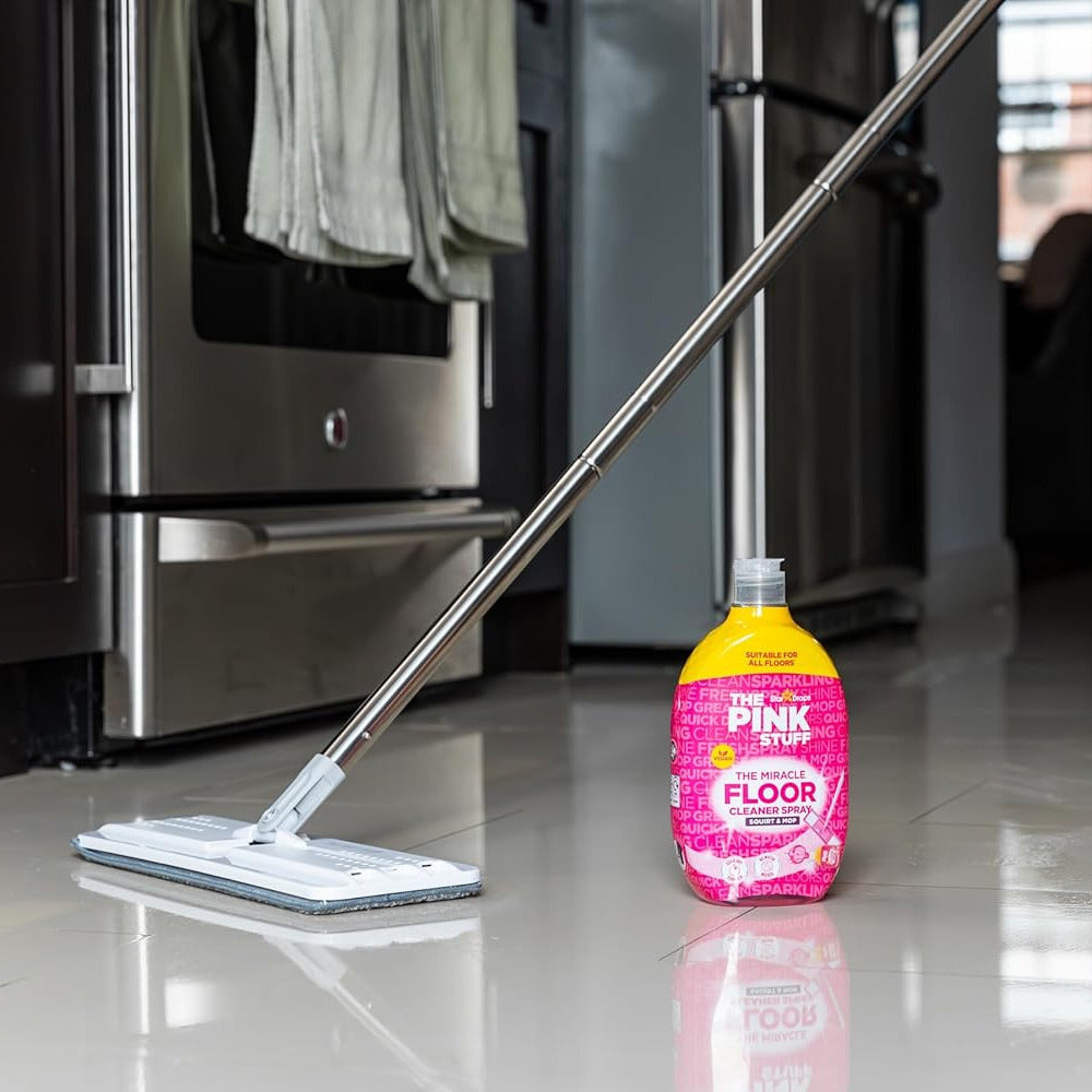 The Pink Stuff The Miracle Floor Cleaner 750ml next to a mop on shiny kitchen tiles.
