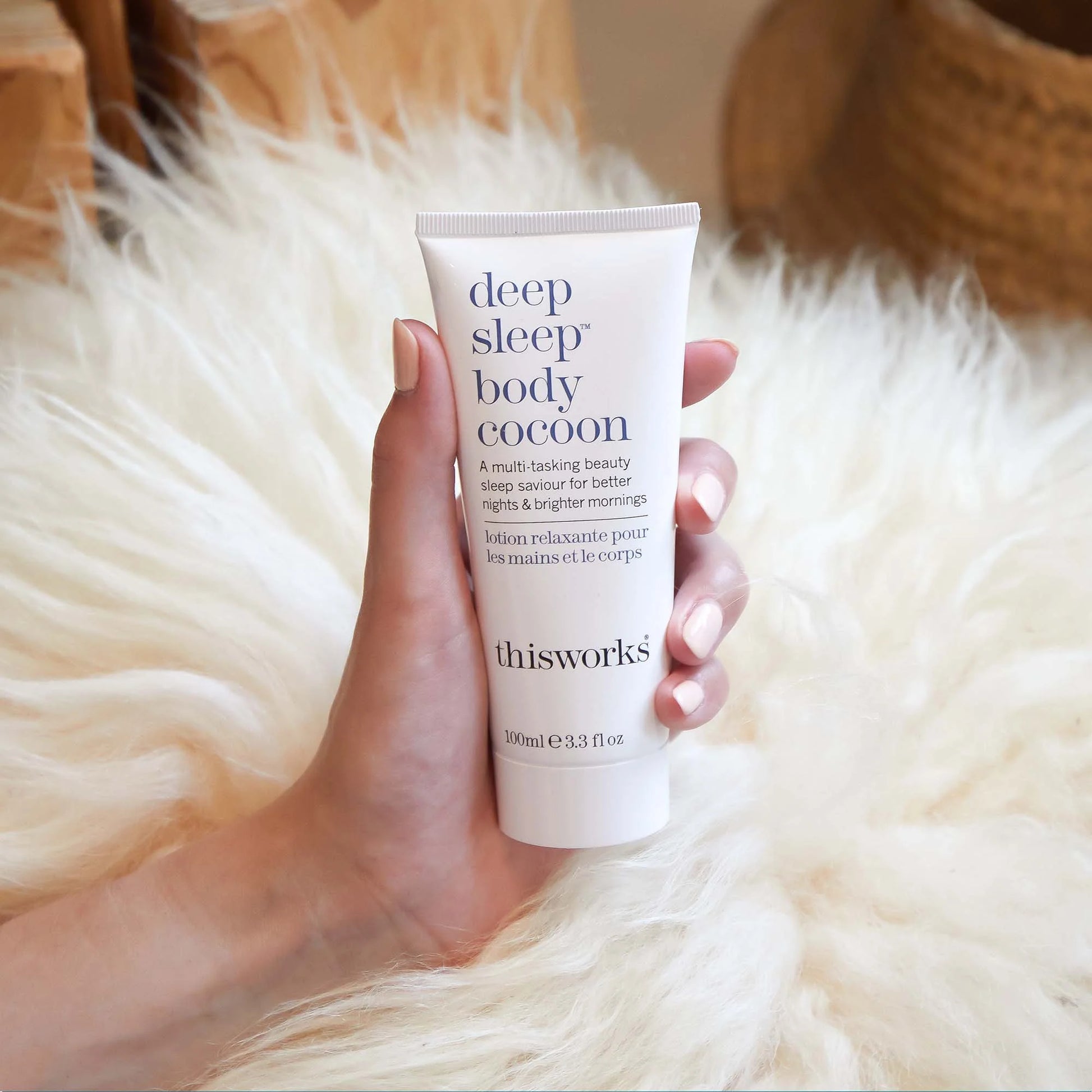 Hand holding thisworks 'deep sleep body cocoon' tube against a fluffy white background
