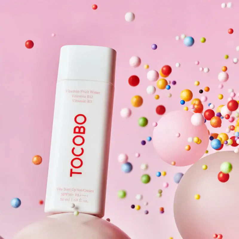 TOCOBO Vita Tone Up Sun Cream SPF50+ in playful, colorful setting with floating spheres.
