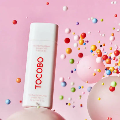 TOCOBO Vita Tone Up Sun Cream SPF50+ in playful, colorful setting with floating spheres.