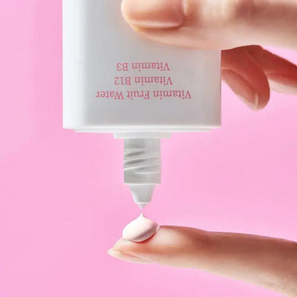 Close-up of TOCOBO Vita Tone Up Sun Cream, featuring Vitamin B3 and B12, on a finger against a pink background.