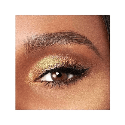 Close-up of an eye with Too Faced gold eyeshadow and long lashes on a white background