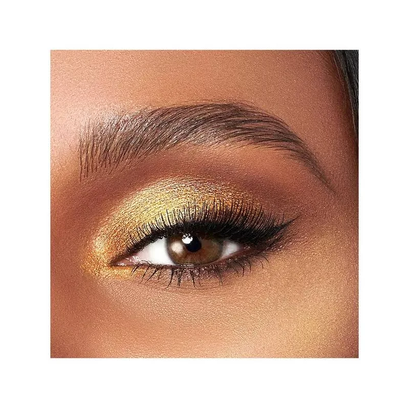 Close-up of an eye with Too Faced gold eyeshadow and long lashes on a white background
