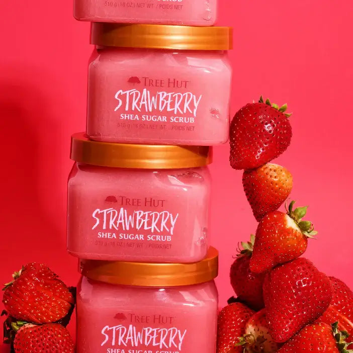 Stack of Tree Hut Strawberry Shea Sugar Scrub jars with strawberries on a red background