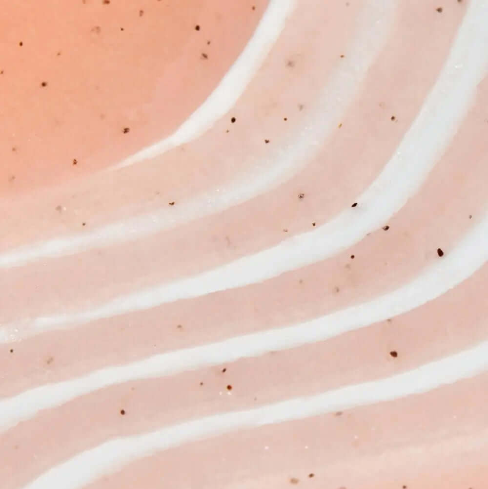 Close-up of a textured, TREE HUT Vitamin C Sugar Scrub pink-colored sugar scrub showing smooth layers and fine particles for exfoliating skin.